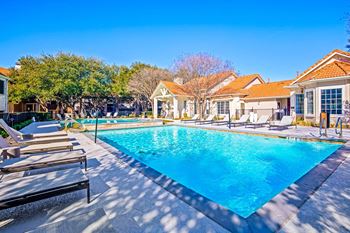 A swimming pool with chairs around it in front of a house